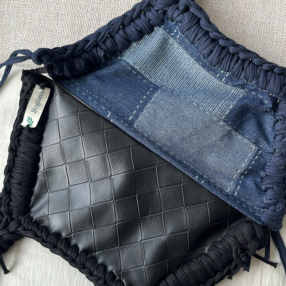 Black textured bag with denim accents on a light gray surface