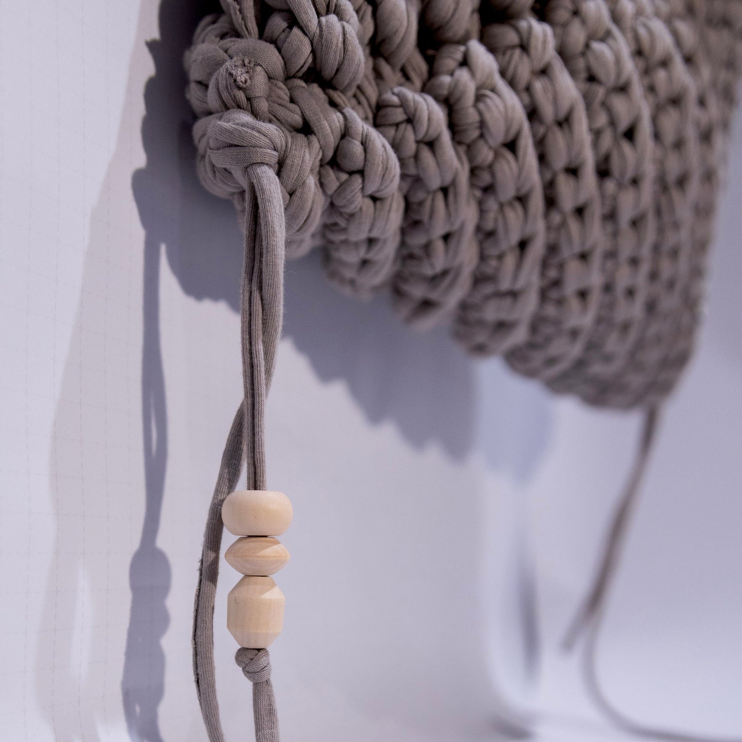 Close-up of a beige woven headband with a wooden bead on a white background