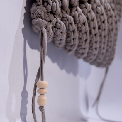 Close-up of a beige woven headband with a wooden bead on a white background