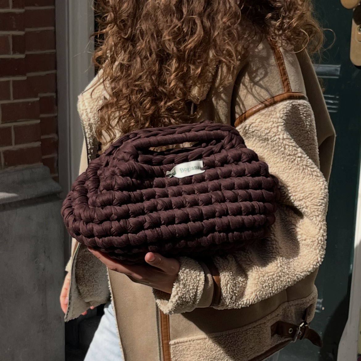 Person holding a textured brown bag outdoors on a staircase