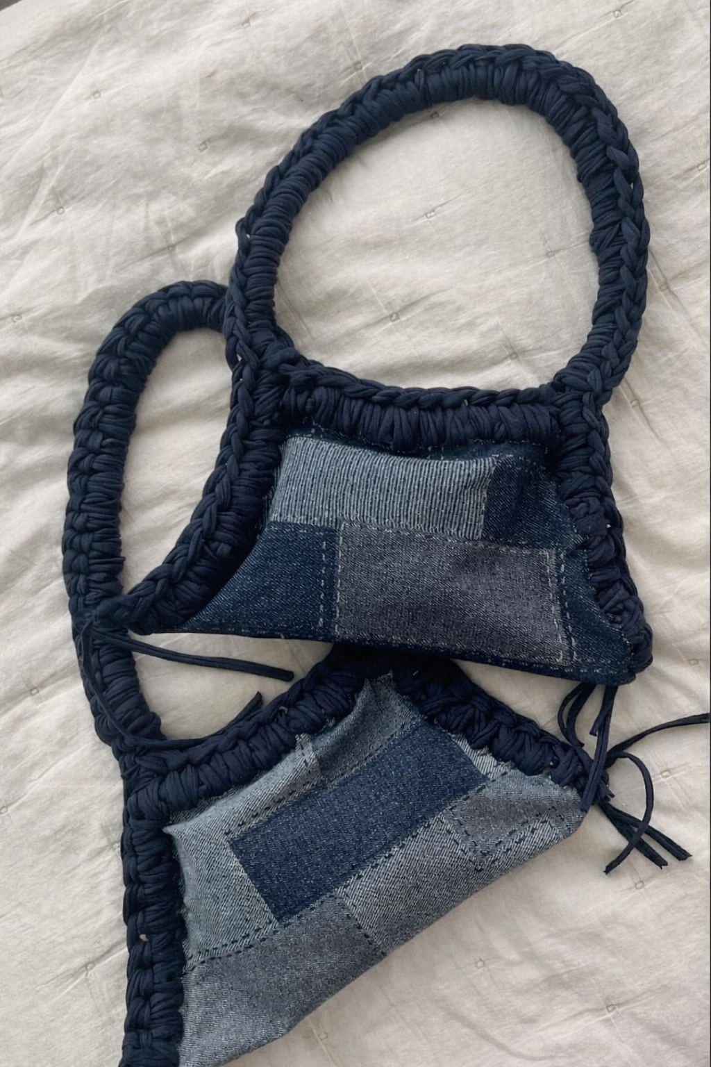 Handmade denim mask with macrame straps on a textured fabric background