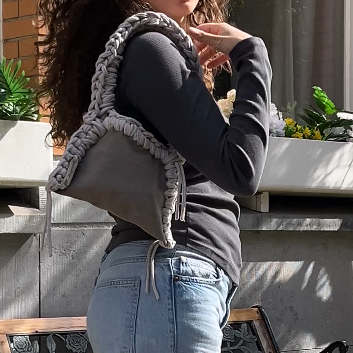 Woman holding a gray handbag outdoors with a blurred background