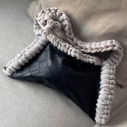 Black bag with braided handle on a light gray couch