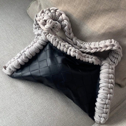 Black bag with braided handle on a light gray couch