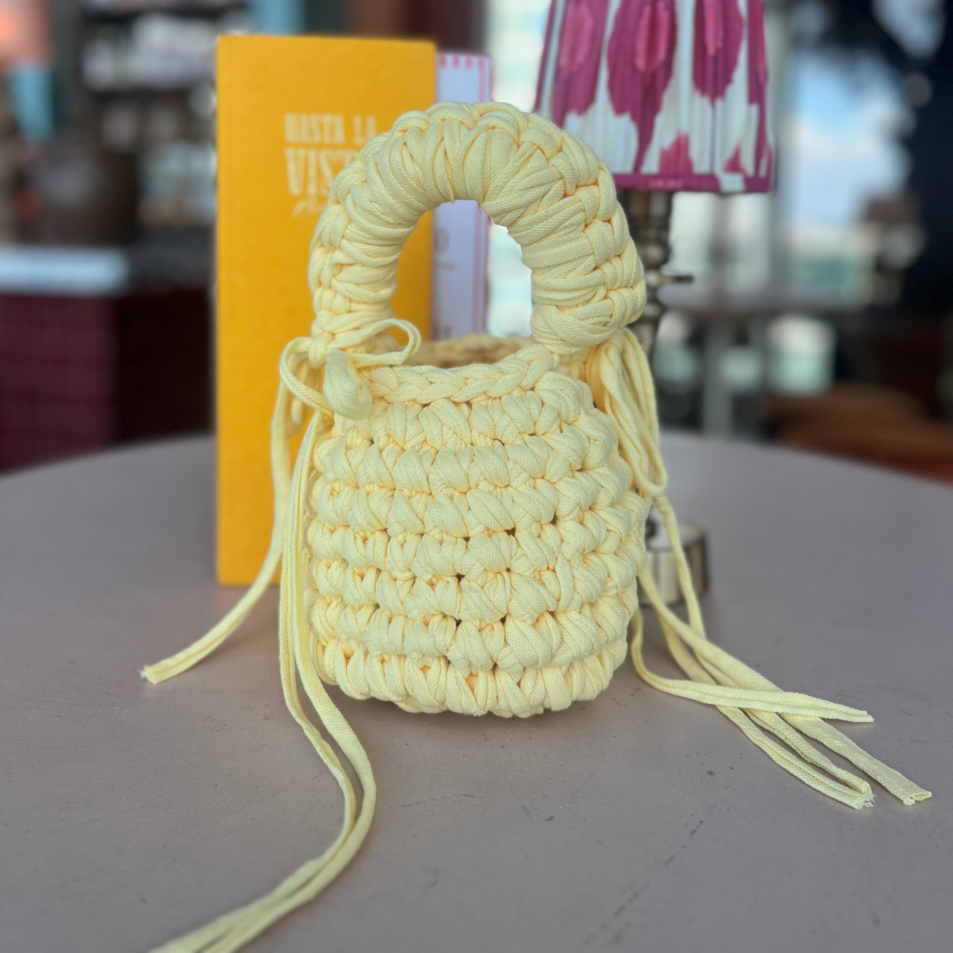 Small woven bag with long strings on a table with a blurred background