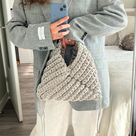 Person wearing a textured beige bag in front of a mirror