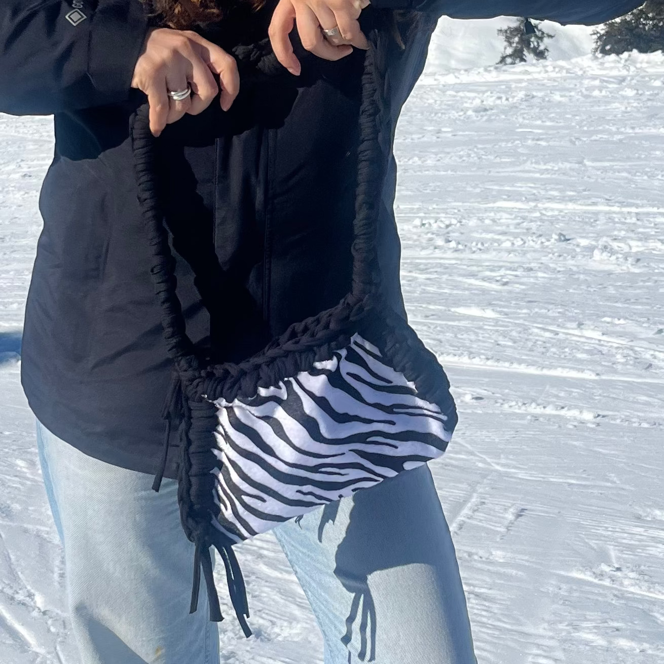 Person posing on a snowy mountain with ski tracks and mountains in the background