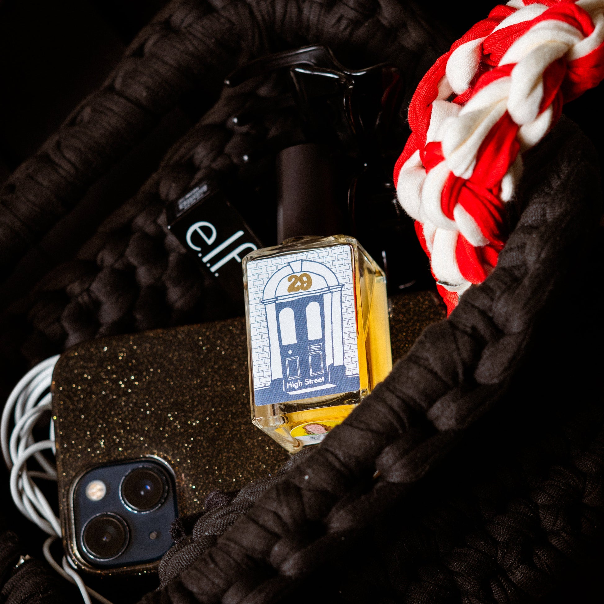 Perfume bottle with a phone and braided cord on a dark background